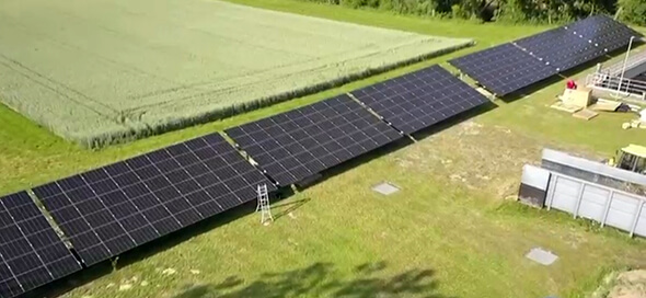 Auf dem Bild sind PV Module auf einer grünen Wiese zu sehen. Die Module sind in geneigt und in einer Reihe aufgestellt. 